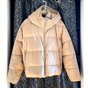 A cute and stylish beige leather puffy winter coat with pockets and a hood.